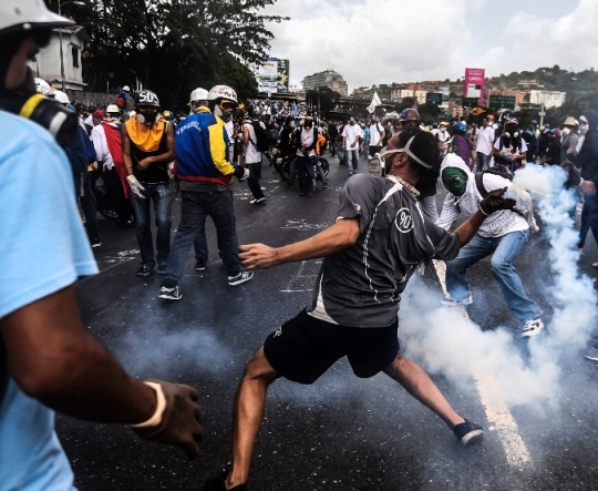 Riot police clash with opposition demonstrators during a protest in Caracas, on May 24, 2017. Venezuela's President Nicolas Maduro formally launched moves to rewrite the constitution on Tuesday, defying opponents who accuse him of clinging to power in a political crisis that has prompted deadly unrest. / AFP / JUAN BARRETO