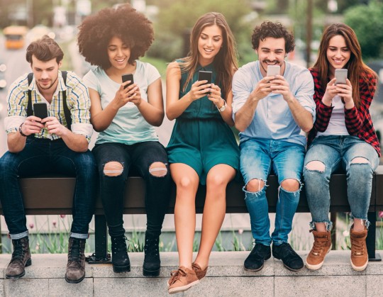 A group of friends surfing the net on a bridge.